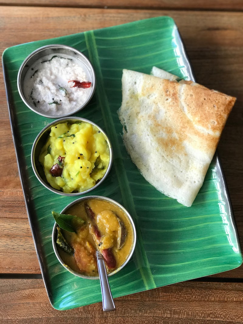 Homemade triangular dosa with chutney, sambar and spicy potatoes