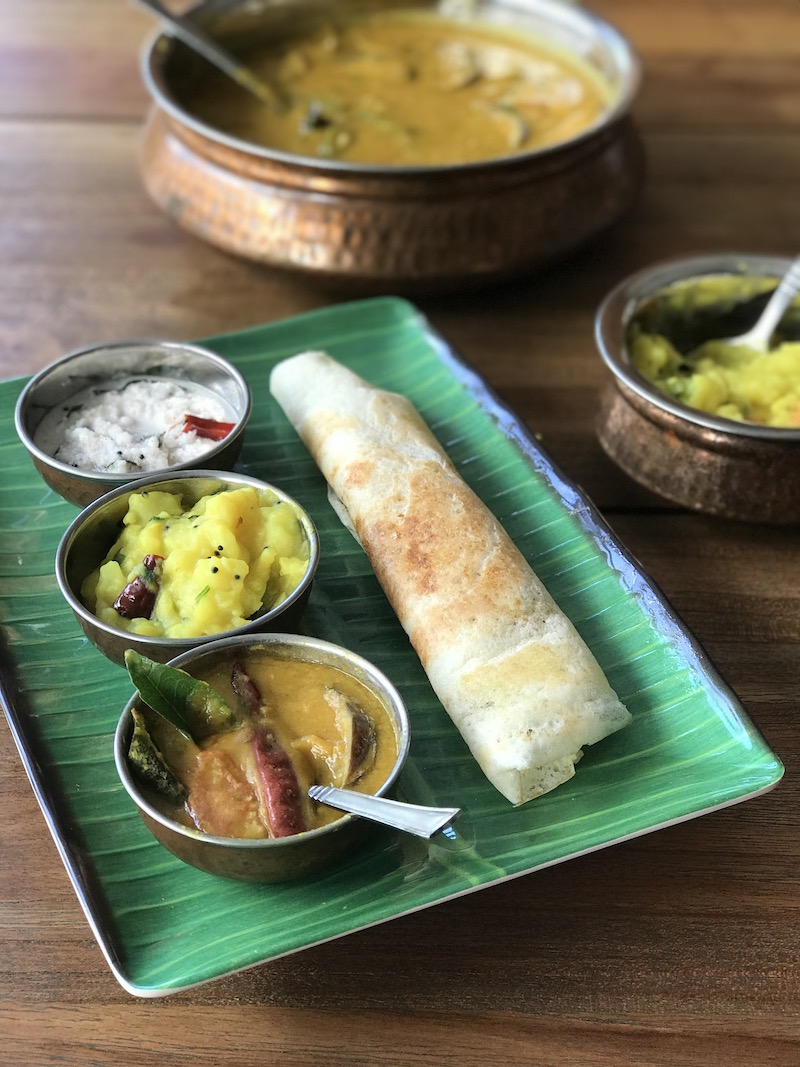 Homemade dosa with chutney, sambar and spicy potatoes